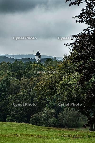 Landschaft mit Bäumen und Blick auf Gebäude mit weißem Glockenturm, in der Nähe des historischen Stadtzentrums von Old-Breinig. Breinig-Stolberg (Rheinland), Noordrijn-Westfalen. Deutschland [IBR125557540]