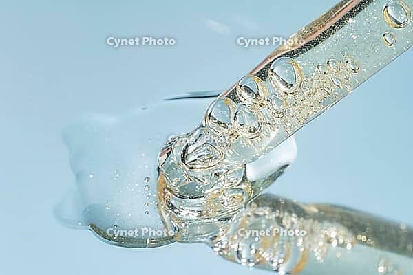 Close up of pipette with pouring liquid serum and shadows on blue background. Trendy cosmetics shot with hard shadows [IBR125557559]