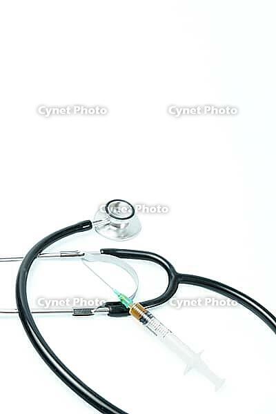 Stethoscope and syringe filled with vaccine liquid on a white background, symbolizing healthcare, prevention, and treatment [IBR125557565]