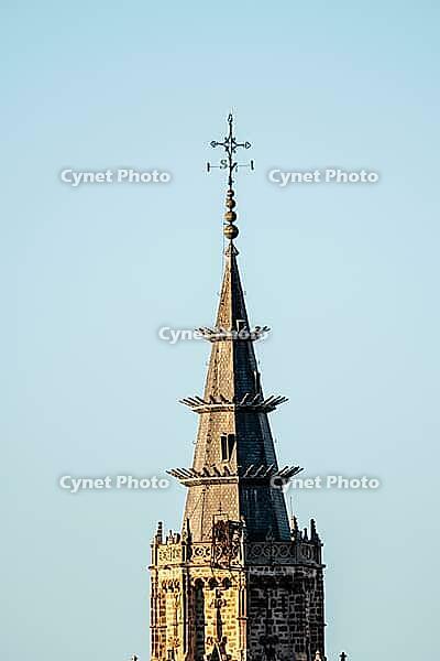 The detailed spire of Toledo Cathedral against a clear sky displays intricate stonework and a weather vane, showcasing Spanish architectural heritage [IBR125557574]