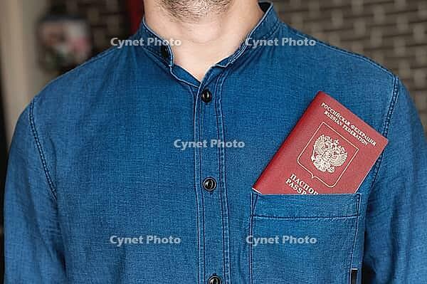 Close-up of a man in a blue shirt, the passport is visible from his pocket. Tourism and travel concept. Selective focus and shallow depth of field [IBR125557617]