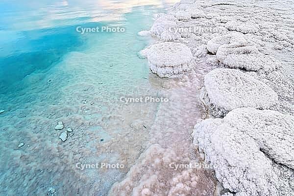 Sand completely covered with crystalline salt on the shore of the Dead Sea, turquoise blue water nearby - typical scenery on a beach in A Bokek, Israel [IBR125566000]