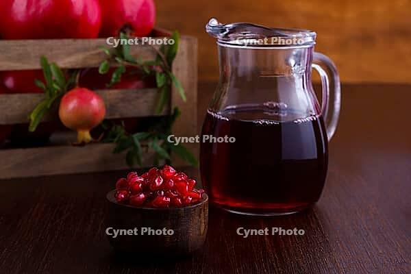 Pomegranate juice and fruits on dark wooden background, selective focus [IBR125566010]