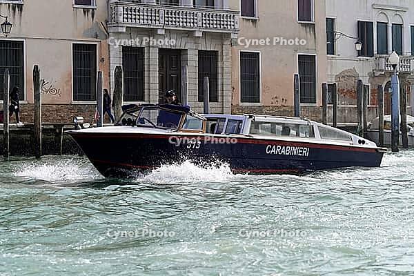 A Carabinieri boat sails through a Venetian canal with a powerful bow wave on historic buildings, Venice, Veneto, Italy [IBR125566037]