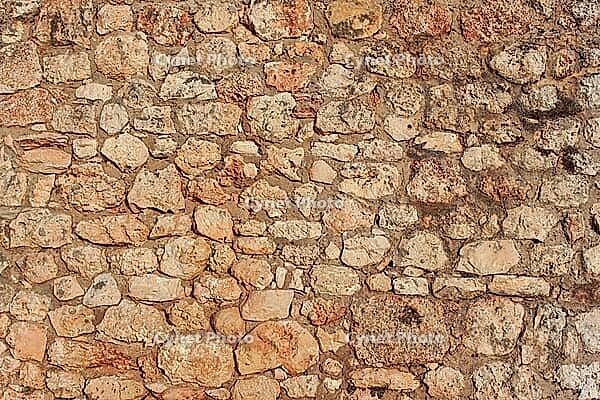 Rough reddish color stone bricks wall, sun shines on [IBR125566044]