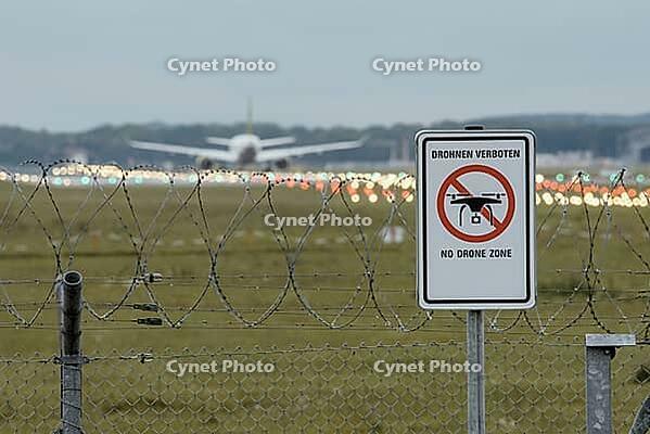 Waning sign NO DRONE ZONE am Zaun des deutschen Flughafens mit stumpfem Passagierflugzeug im Hintergrund [IBR125566051]