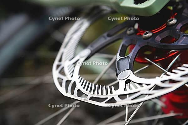 Close-up of Hydraulic bicycle disc brakes, gray metal disc attached to a bicycle wheel close-up, effective popular mountain bike brakes. Bicycle spokes on a gray background [IBR125566067]