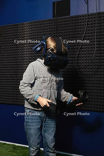 6 years old boy in virtual helmet learning how to control game with controllers [IBR125566079]