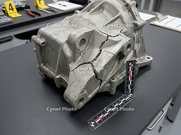 A fractured metal component rests beside forensic measurement scales, with numbered evidence markers and inspection paperwork on the workbench, AI generated [IBR125592703]