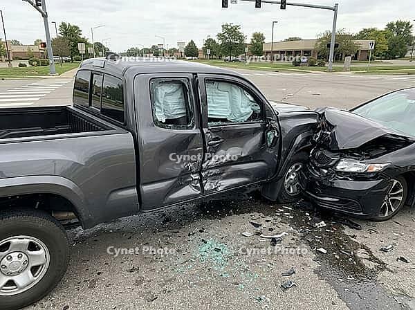 Broken glass, debris, and dark fluid cover the pavement beneath deployed airbags, as damaged vehicles block part of a signalized intersection, AI generated [IBR125592707]