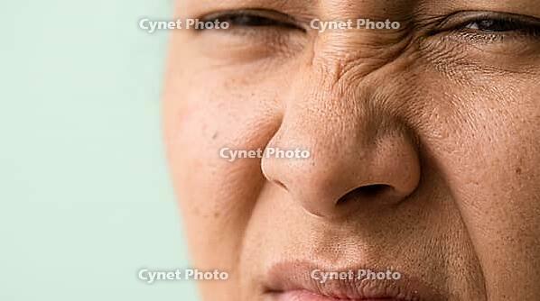 Close-up of adult scrunched nose with wrinkles across the bridge and raised upper lip, nose wrinkler muscle action, cropped face, copy space, AI generated [IBR125592728]