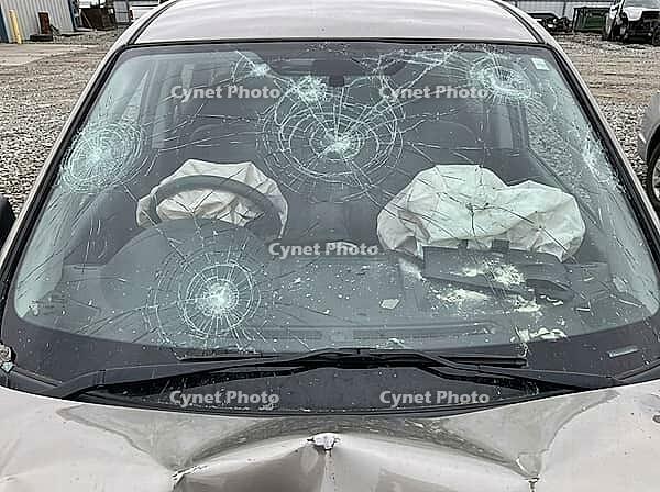 Impact fractures spread across the windshield, with both front airbags inflated and glass fragments visible on the dashboard and hood, AI generated [IBR125592739]