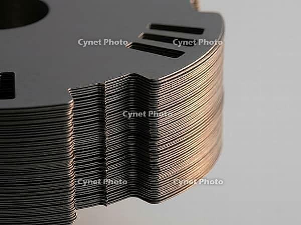 Precision-cut steel sheets reveal fine layered edges and punched slots, with a smooth metallic finish set against a plain background in a detailed close-up, AI generated [IBR125592744]