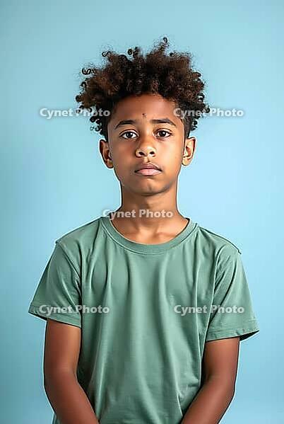Sad pre-adolescent boy with curly hair posing in a studio with a light blue background, AI generated [IBR125621278]