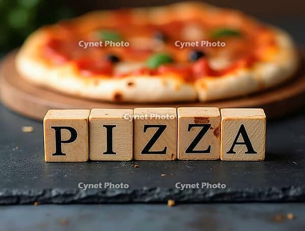 Wooden cubes with the word pizza spelled out on them are placed on a black slate surface, with a freshly baked pizza in soft focus behind, AI generated [IBR125621286]