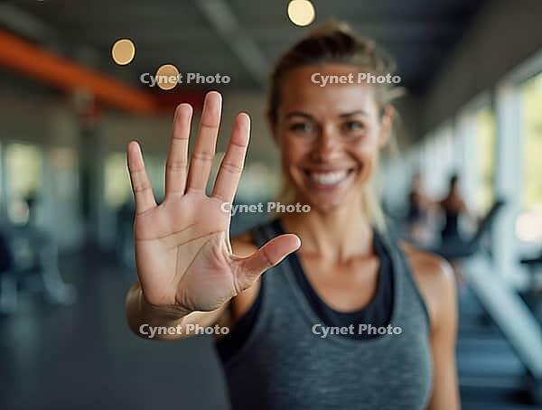 Sportswoman showing stop sign with hand and smiling in gym, AI generated [IBR125621296]