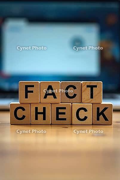 Wooden blocks spelling fact check in front of a blurred laptop screen, AI generated [IBR125621307]