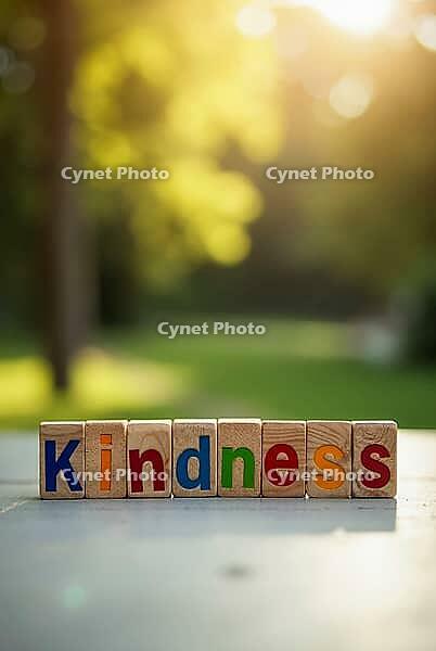 Colorful wooden toy blocks spelling kindness with a blurred park background and bright sunlight bokeh, AI generated [IBR125621368]