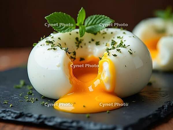 Opened poached egg dome with runny yolk, herbs, and mint presented on a slate plate, creating a gourmet culinary scene, AI generated [IBR125636885]