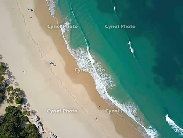Aerial view of turquoise ocean waves washing a white sand beach in a tropical paradise, AI generated [IBR125636894]