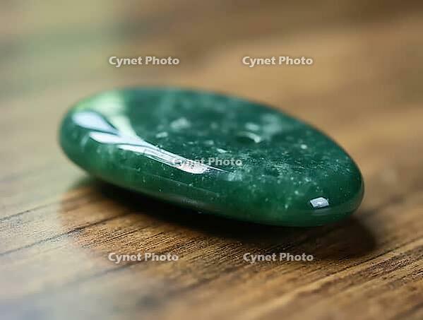 Polished green gua sha stone sits on wooden table, promoting wellness, self-care, and relaxation, AI generated [IBR125636899]