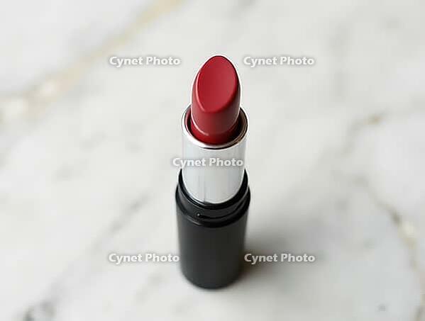 Red lipstick in black and silver tube standing on a marble surface, beauty product, AI generated [IBR125636929]