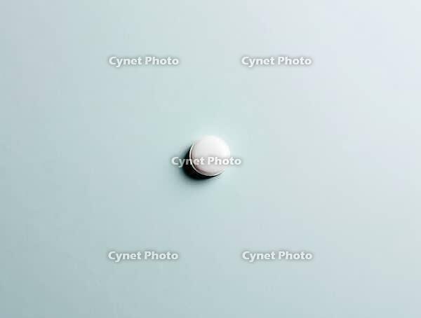 Single white pill rests on a serene light blue backdrop, creating a minimalist composition, AI generated [IBR125636945]