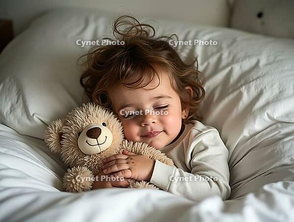 Cute child waking up and hugging teddy bear in bed in the morning, AI generated [IBR125645883]