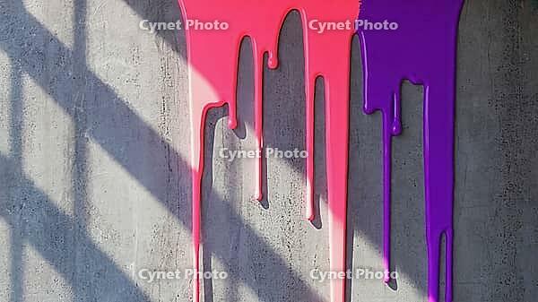 Pink and purple paint flowing down a gray concrete wall, creating a vibrant and abstract pattern with rich textures and contrasts, AI generated [IBR125653411]