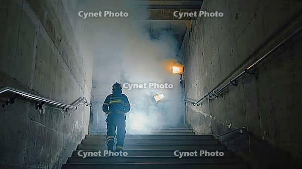 Brave firefighter ascending smoke filled staircase in burning building, demonstrating courage and dedication in life threatening situation, AI generated [IBR125653419]