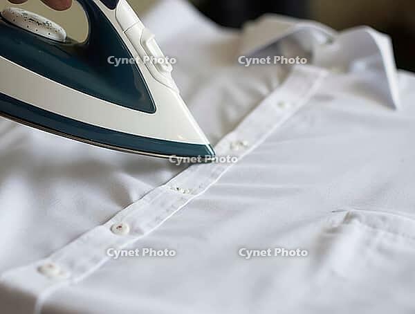 Close-up of a steam iron gliding over a crisp white shirt, removing wrinkles and creating a smooth, professional look, AI generated [IBR125653423]