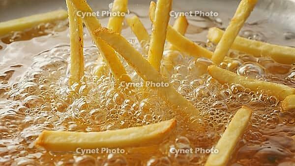 Close up of french fries being submerged in hot oil, creating bubbles and sizzling sounds, during fast food preparation, AI generated [IBR125653443]