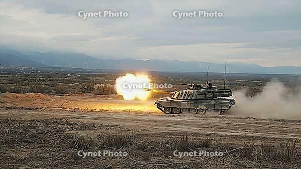 Powerful military tank firing a shot, creating a bright flash and dust cloud in a desert training ground, AI generated [IBR125653466]