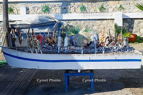 A boat-shaped grill stands over the embers and is equipped with numerous fish, Estepona, Costa del Sol, Andalusia, Malaga province, Spain [IBR125657379]