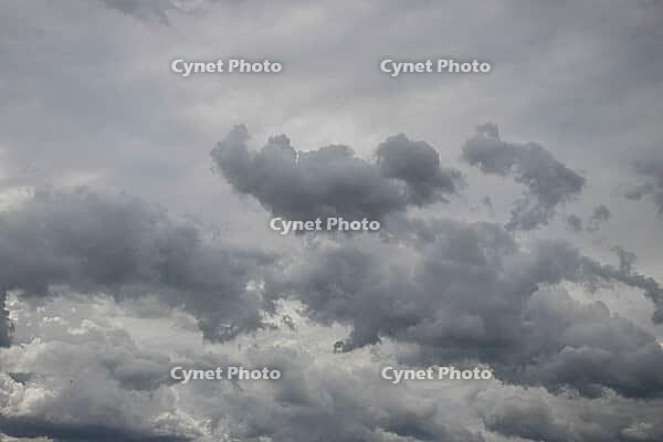 A broad expanse of layered gray storm clouds fills the sky, with darker clouds gathered near the center [IBR125657406]